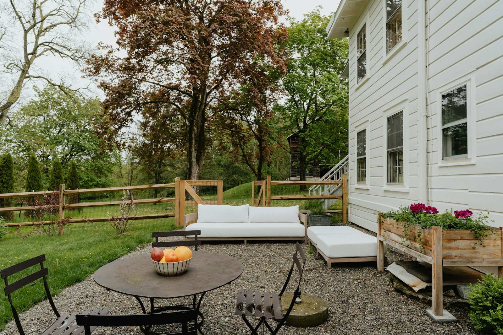 Gravel terrace with a lounge and bistro table beside a white house